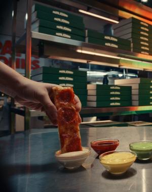 Pizza being dipped into garlic dip
